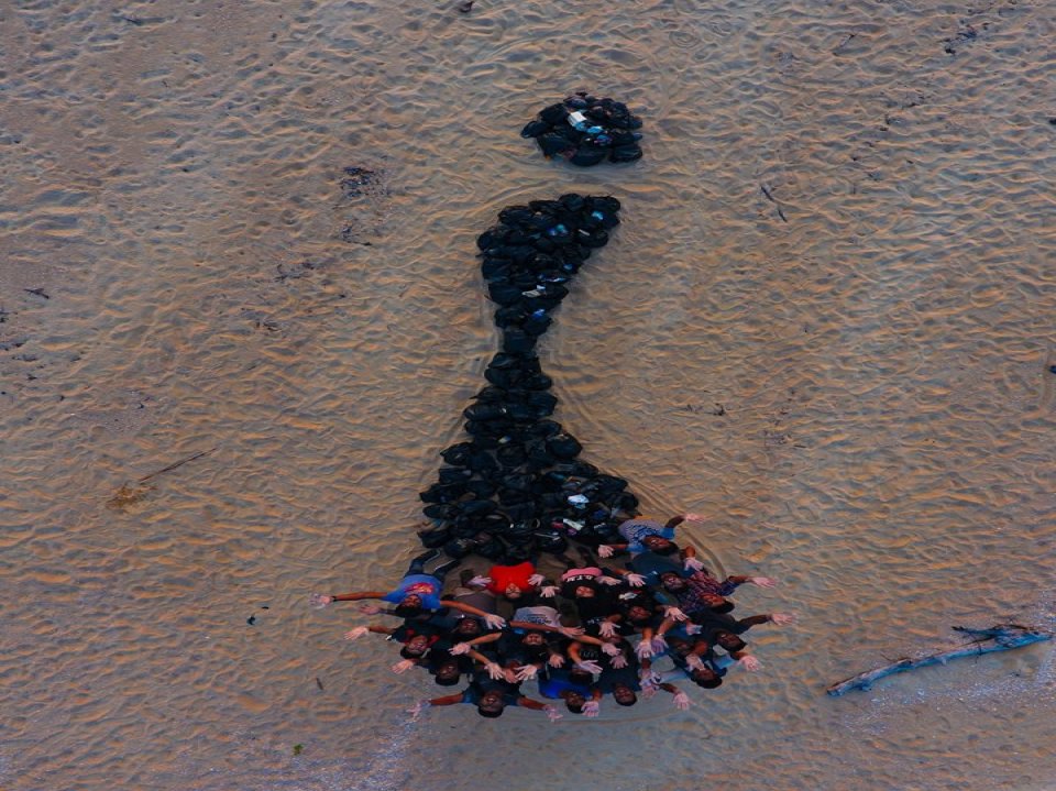 Students forming a design on the beach at sunset
